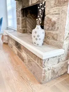 Angled view of ivory hearth padding installed on large stone fireplace.