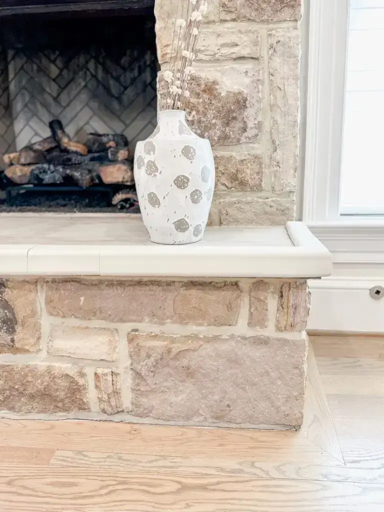Close-up of ivory hearth pad corner installed on large stone fireplace.