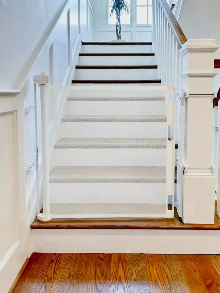 White retractable gate installed at bottom of staircase on the main floor of home.