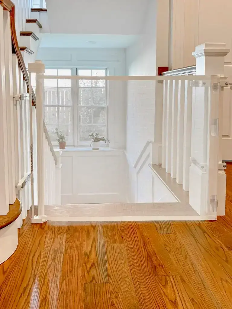 White retractable gate installed on the main floor stairs going down to basement in a beautiful foyer.