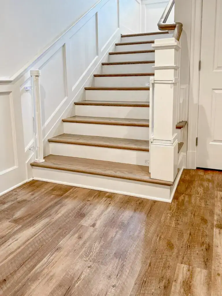 Retractable gate and oversized post mounts installed on bottom of staircase in basement, open.