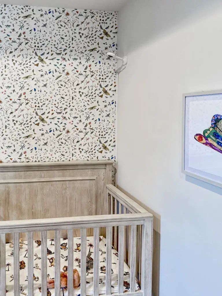 Nanit baby monitor mounted on wall in nursery next to crib.