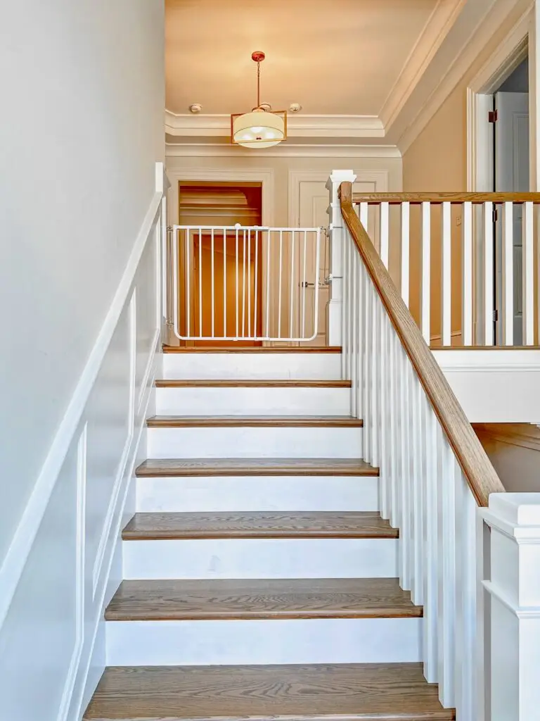 White stairway gate at the top of the staircase in second floor hallway closed securely.