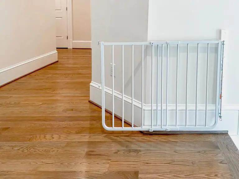 White stairway gate leaning against wall, open, in second floor hallway.