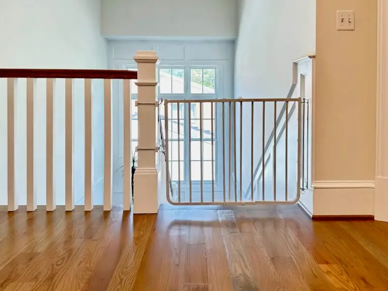 White stairway gate installed in second floor hallway with custom post mounts on oversized post.