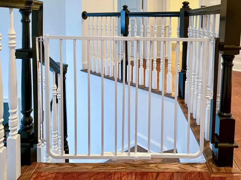White stairway gate and black post mounts installed on top of staircase