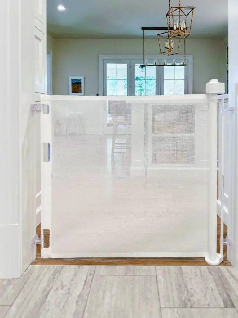 White retractable gate installed in kitchen doorframe, closed.