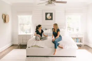 Two baby proofers sitting on a bed, discussing safety principles.