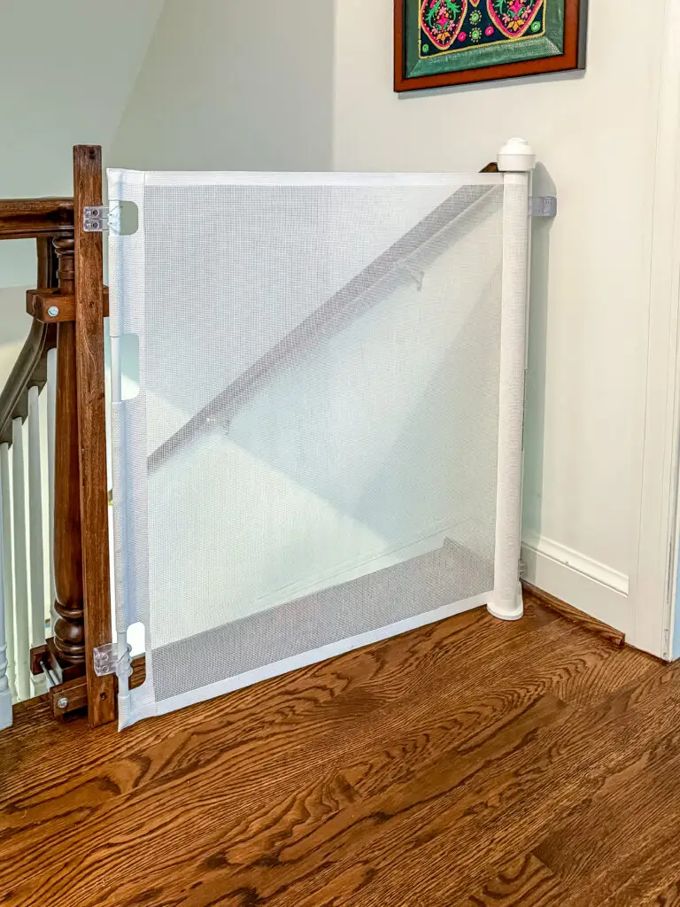 White retractable gate at the top of the staircase, mounted with custom-stained post mounts, in a bethesda, md home