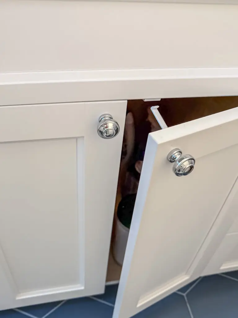 Cabinet latch installed inside a white bathroom vanity cabinet in a bethesda, md home