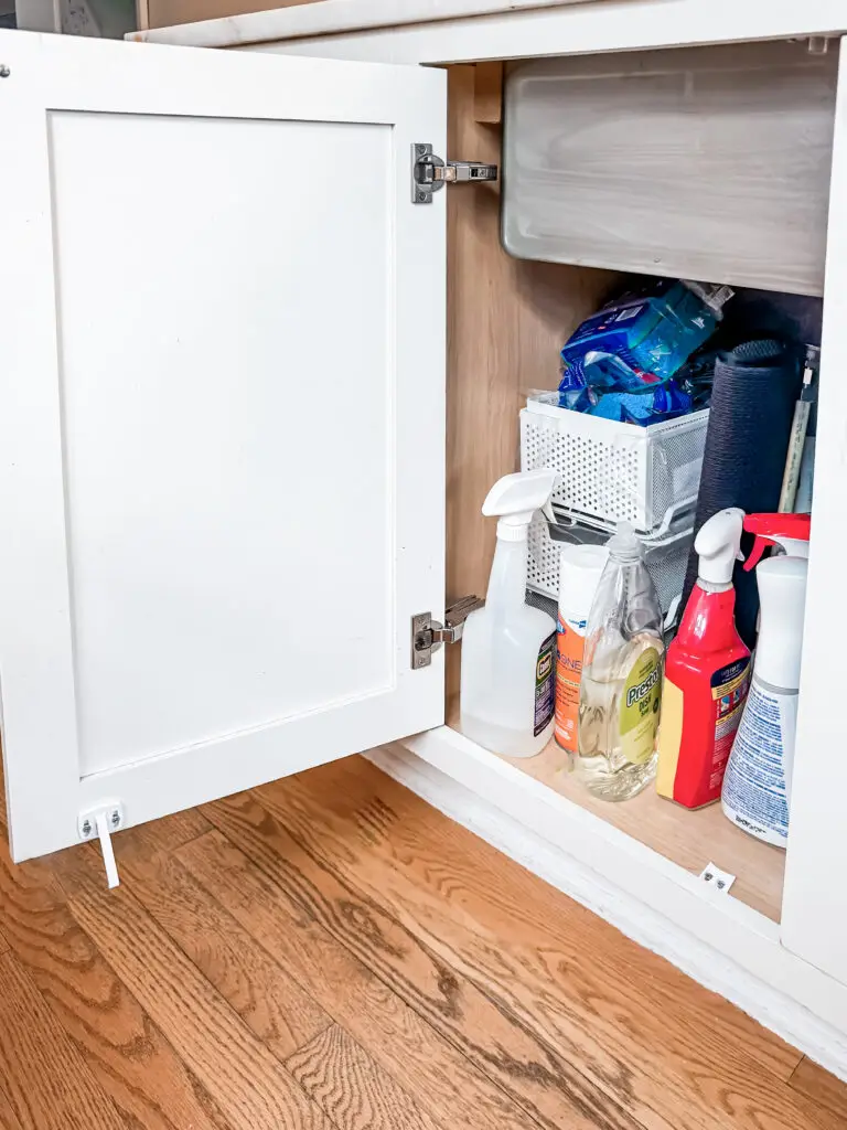 Cabinet latch installed inside an under-sink kitchen cabinet