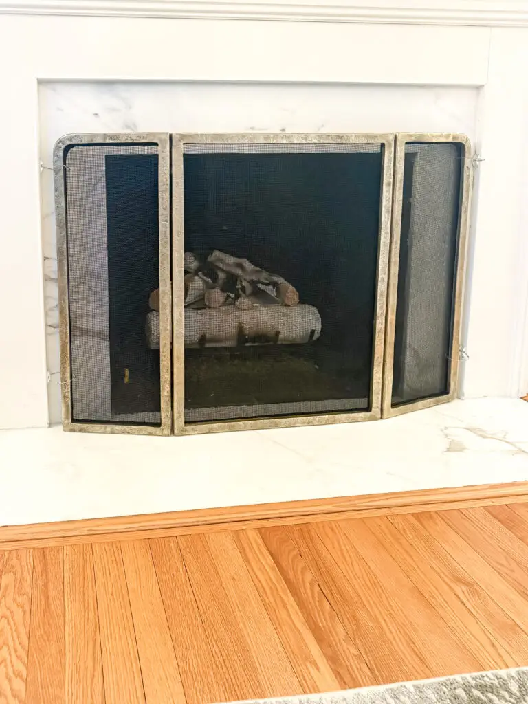 Secured fireplace screen covering the firebox of a marble-surround fireplace