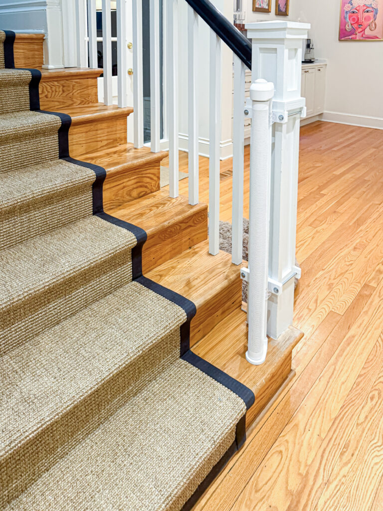 Retractable gate retracted out of the way at the bottom of a sisal-runner staircase