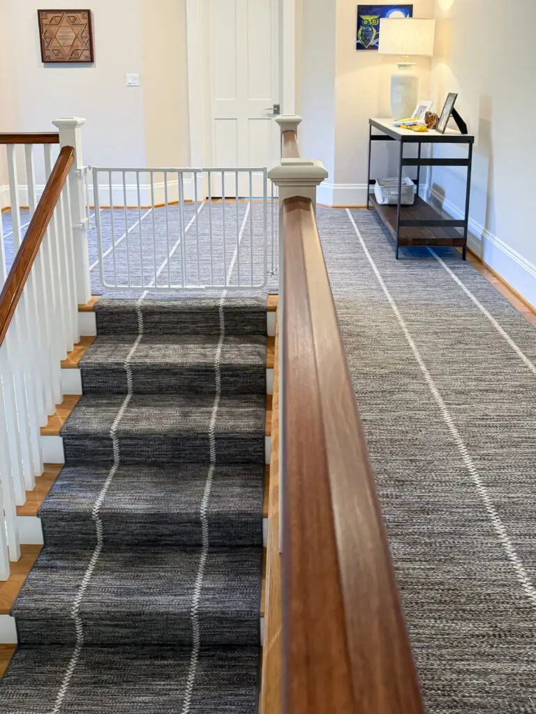 White stairway gate at the top of the stairs with custom mounts wrapped around the oversized newel posts