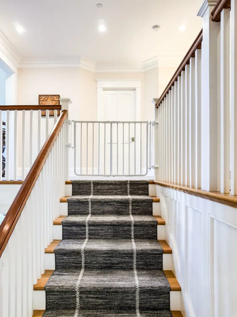 White hardware-mounted stairway gate at the top of the second-floor staircase in a bethesda, md home