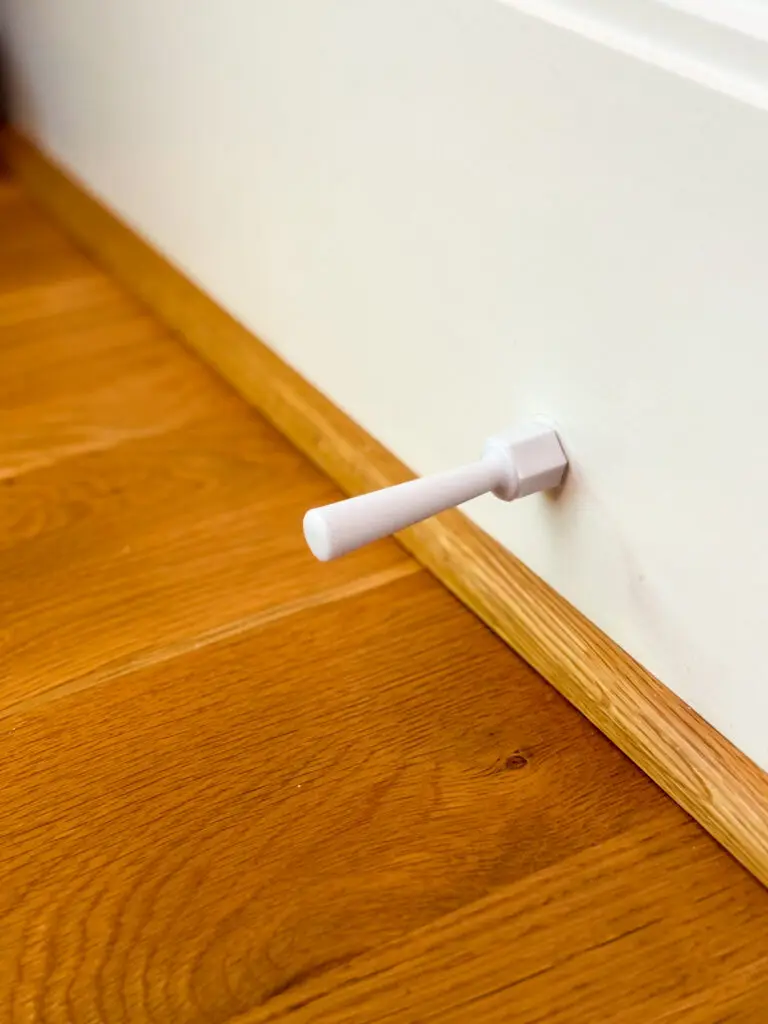 Child-safe one-piece door stop installed on the baseboard