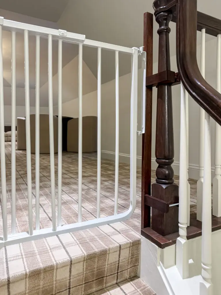 Close-up of a white stairway gate on custom-stained mounts fitted to a dark newel post in a maryland home