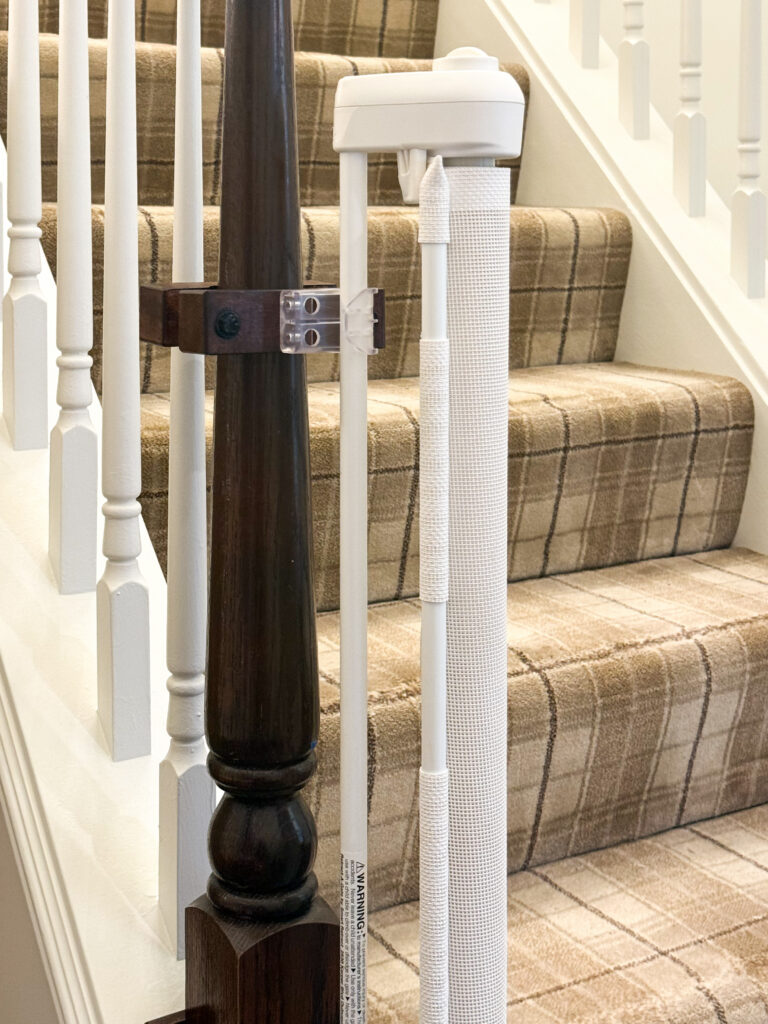 White retractable gate post mounted to a turned newel post with dark-stained mounts