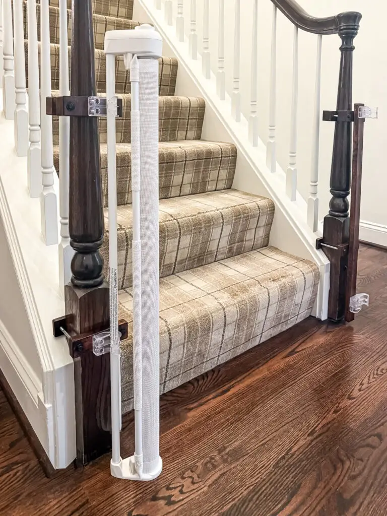 White retractable gate mounts on a dark newel post at the base of the third-floor stairs in a maryland home