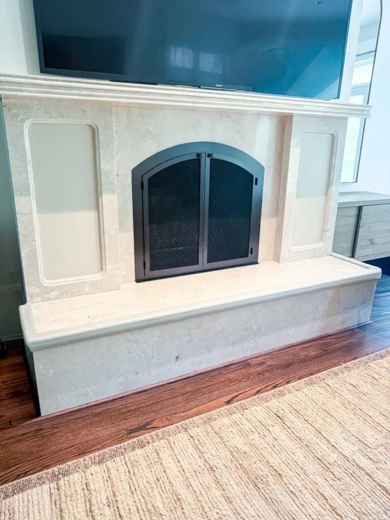 Arched stone fireplace with ivory hearth padding along the raised hearth edge in a maryland family room