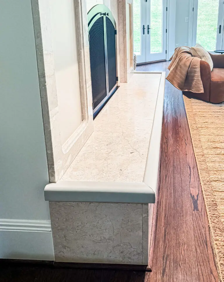 Close-up of ivory hearth padding wrapped around the corner of a raised stone hearth