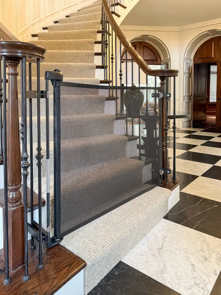 Black retractable gate closed across the bottom of the formal foyer staircase