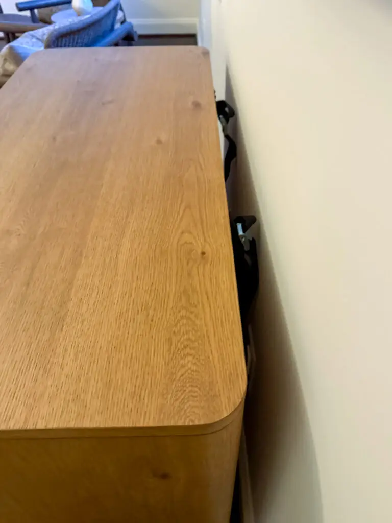 Furniture strap anchoring a dresser to the wall