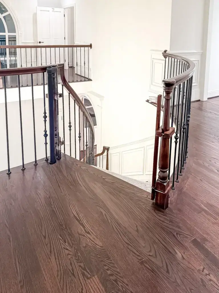 Second-floor landing with an iron-baluster railing above the curved marble staircase
