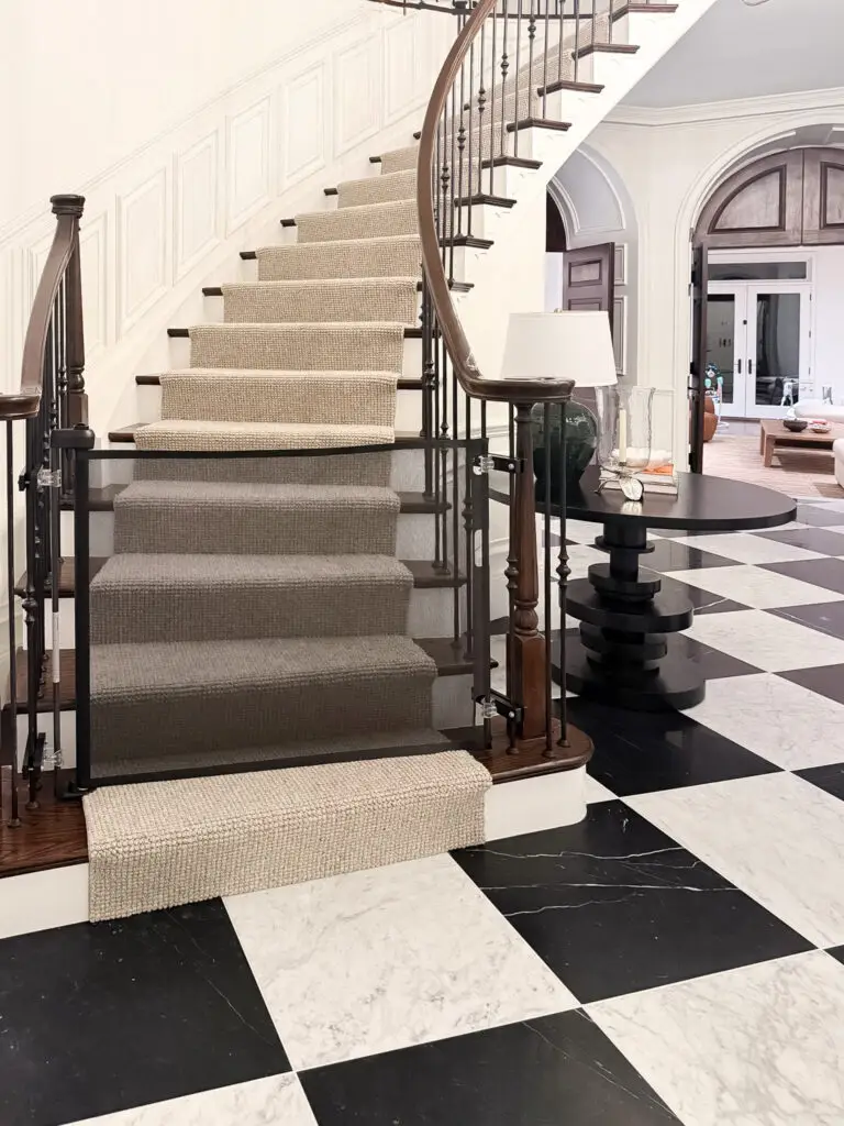 Black retractable gate at the foot of a curved foyer staircase with wrought iron spindles in a maryland home