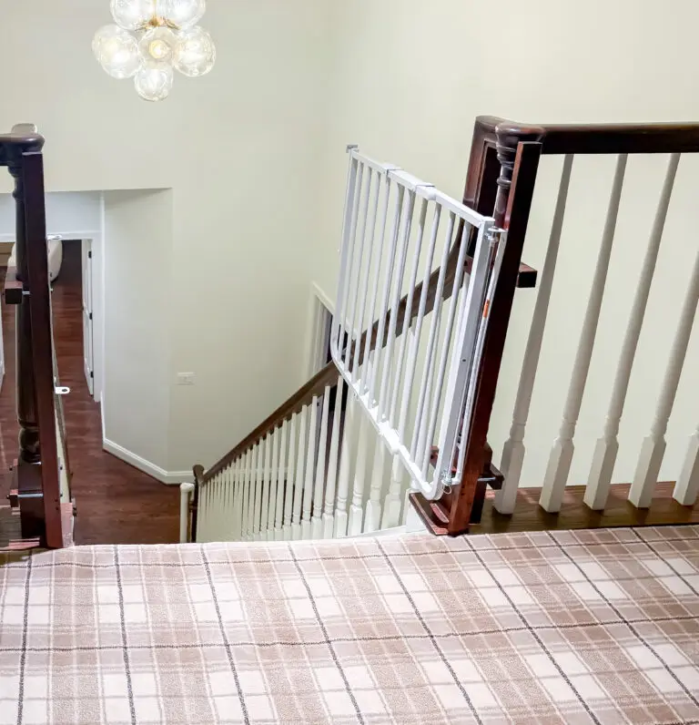 White hardware-mounted stairway gate at the top of the third-floor stairs with custom-stained post mounts in a maryland home