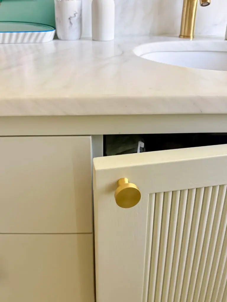 Cabinet latch on a bathroom vanity door, shown open