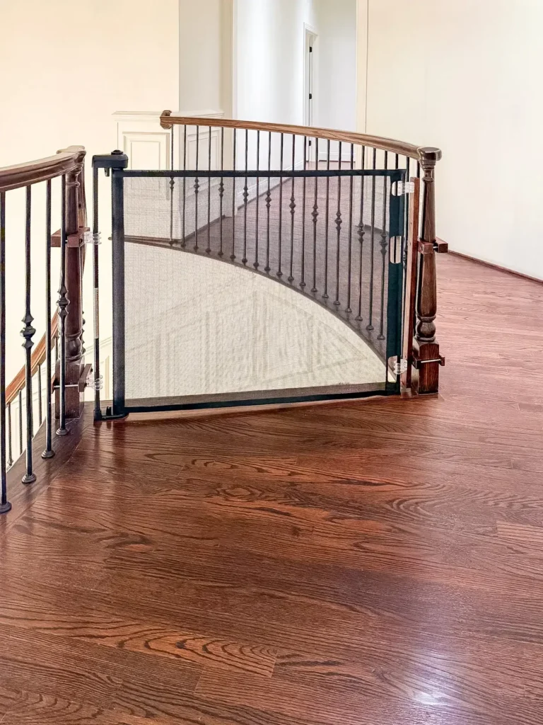 Black retractable gate at the top of the curved staircase with iron balusters on the second floor of a maryland home